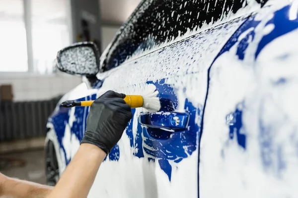 車のディテールサービスで泡と車のボディの手ブラシ洗浄 洗車場労働者が車体を洗う — ストック写真