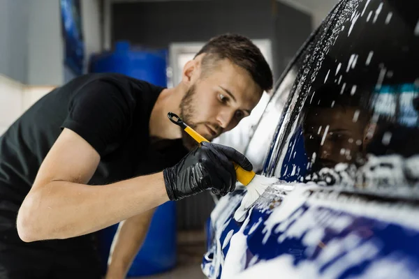 Araba yıkama servisinde köpüklü el fırçası. Araba yıkama işçisi bir arabayı yıkar.