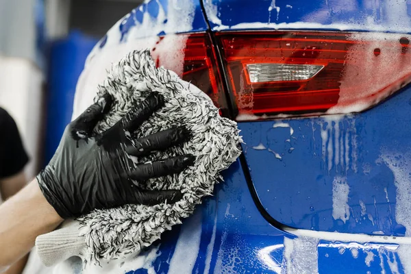 ガレージに泡車のボディとマイクロファイバー手袋で手を洗う 自動車詳細サービスで手動フォーム洗浄を行う車の洗濯機 — ストック写真
