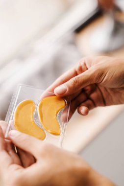 Elinde peptit ve hyaluronik asit olan altın hidrojel göz bantları. Kırışıklıkları gidermek için yakın plan altın işlemeler, göz altındaki şişliği ya da torbaları çıkarmak için.