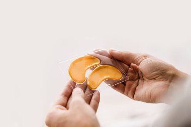 Kırışıklıkları gidermek için yakın plan altın işleme seti, göz altındaki şişliği ya da torbaları çıkarmak için. Elinde peptit ve hyaluronik asit olan altın hidrojel göz bantları.