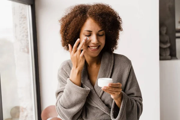 Mujer Afroamericana Albornoz Con Crema Hidratante Facial Haciendo Rutina Belleza — Foto de Stock