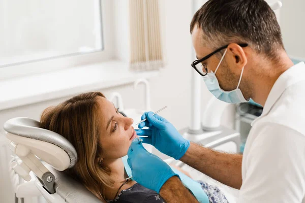 Dentist examines teeth of woman for treatment of toothache. Pain in teeth. Consultation with dentist in dentistry