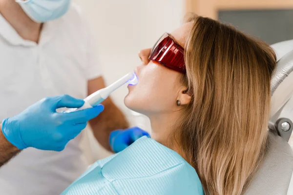Dentysta Leczy Usuwa Próchnicę Pacjentki Oświetlenie Fotopolimerowej Procedury Napełniania Zębów — Zdjęcie stockowe