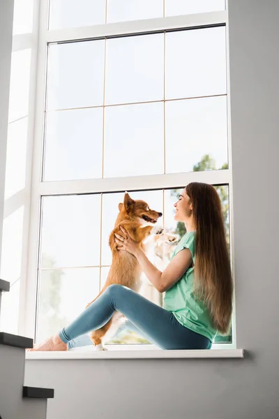 Schwangere Sitzt Auf Der Fensterbank Und Umarmt Ihren Hund Corgi — Stockfoto
