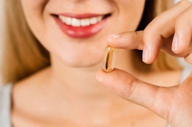 Dudakların yakınında Omega 3 hapları var. Biyolojik olarak aktif besin takviyelerinin BADS kapsülü. Sağlıklı kemikleri inşa etmek ve korumak için D vitamini