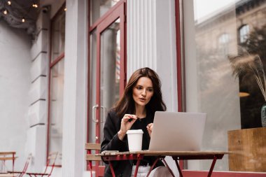 Takım tartışması ve problem çözme. Dizüstü bilgisayarı olan kız menajer, dışarıda kafede trendleri ve görevleri tartışıyor. İş arkadaşları ve iş ortaklarıyla çevrimiçi video toplantısı