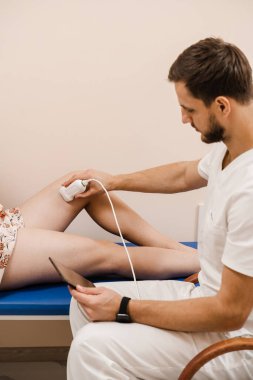 Legs ultrasound scan veins and arteries of woman. Vascular surgeon examines veins and arteries of legs of girl in medical clinic