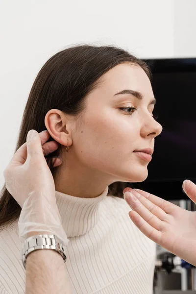Otoplasty is surgical reshaping of the pinna, or outer ear for correcting an irregularity and improving appearance. Surgeon doctor examines girl ear before otoplasty cosmetic surgery