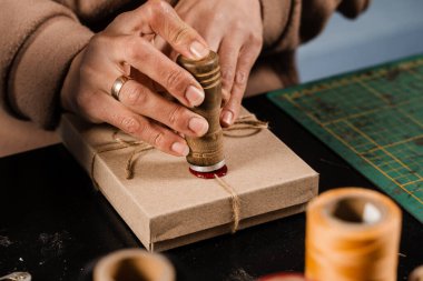 Craftsman puts a stamp on sealing wax on handmade gifts in the workshop. Process of sealing waxing on gift packaging in workshop