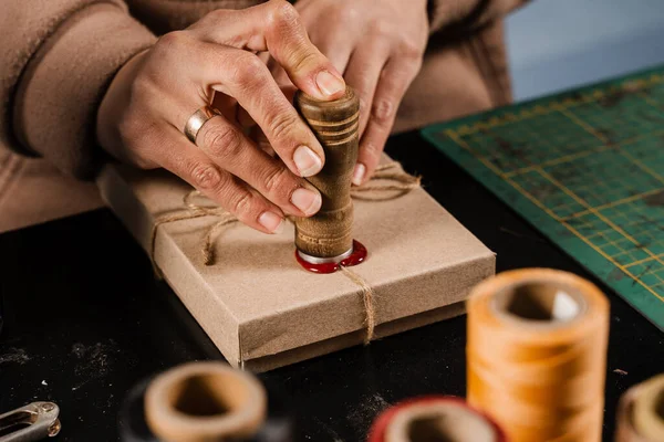Craftsman puts a stamp on sealing wax on handmade gifts in the workshop. Process of sealing waxing on gift packaging in workshop