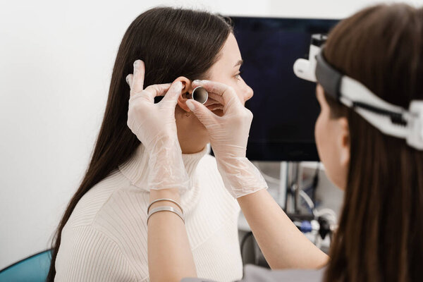 Examination of womans ear with ear funnel. Otoscopy. Visit to ENT doctor and consultation
