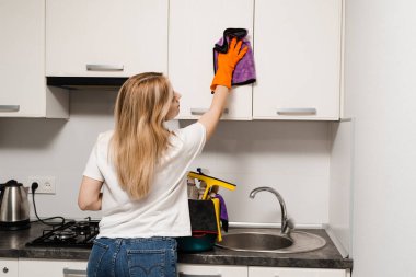 Cleaning woman is wiping kitchen with microfiber rag. Professional cleaning service for general house cleaning. Housewife cleans the kitchen from dirt and dust