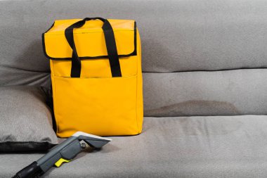 Extractor dry cleaning machine for removing stains and dirt from couch at home. Professional cleaning service. Professional dry cleaning machine and yellow transport bag