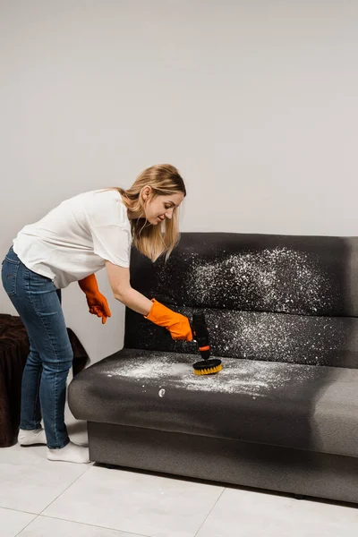 Applying detergent on couch for dry cleaning using extractor machine. Process of dry cleaning for removing stains and dirt from couch at home. Professional cleaning service