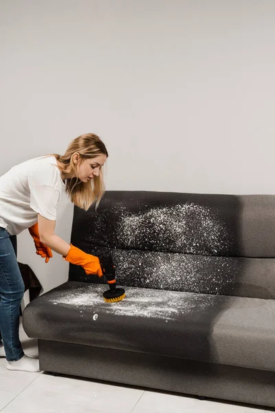 Applying detergent on couch for dry cleaning using extractor machine. Process of dry cleaning for removing stains and dirt from couch at home. Professional cleaning service