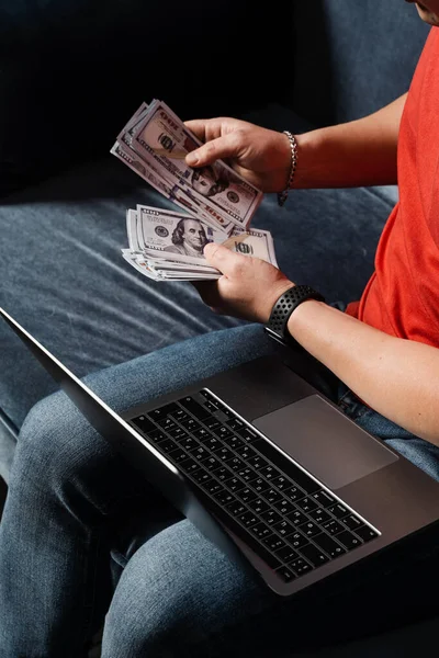Winner in online casino is counting money won. Man with laptop is counting cash dollars and win online bet