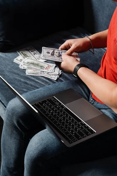 Man with laptop is counting cash dollars and win online bet. Winner in online casino is counting money won