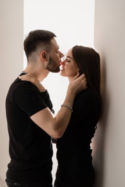 Relationships, feelings and tenderness in the young family of men and girl. Love story of a couple spending time in cozy room at home. Couple in love hugging and kissing on couch at home