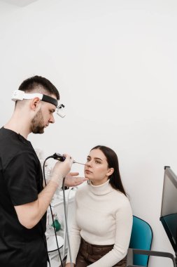 Burun endoskopisi. Gergedan bilimi prosedürü. Kulak farlı KBB doktoru, burunlu kadın hastayı tedavi ediyor.
