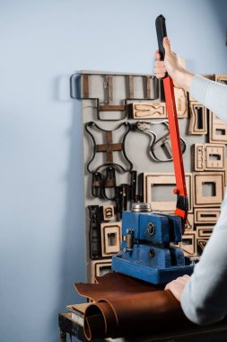 Craftsman is using leather punching press for creating forms from genuine leather. Process of creating genuine leather products in factory