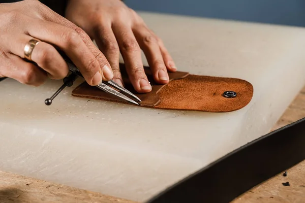 Process of creation genuine leather product. Craftsman is cutting genuine leather using cutter knife for creation natural leather products. Equipment for genuine leather production in workshop