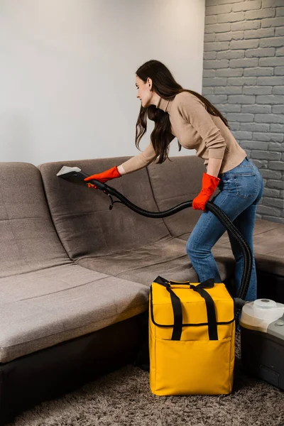 Dry cleaning extractor machine is spraying water and detergent close-up. Professional domestic cleaning service worker is removing dirt and dust from couch using dry cleaning machine