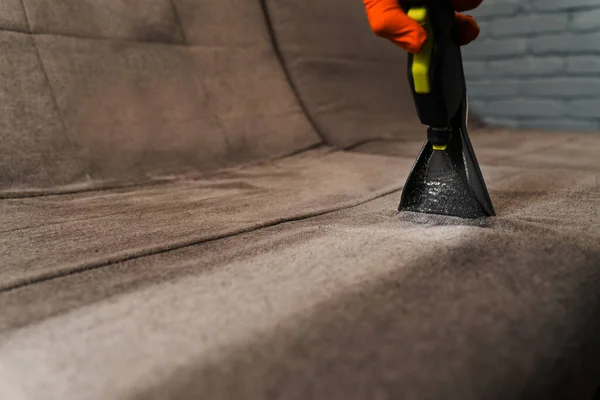 Line on couch after spraying water of dry cleaning extractor machine close-up. Domestic cleaning service cleaner is removing dirt and dust from couch using dry cleaning extraction machine
