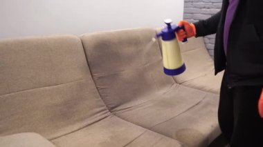 4k video spraying detergent on couch for dry cleaning using extractor machine. Process of dry cleaning for removing stains and dirt from couch at home. Professional cleaning service