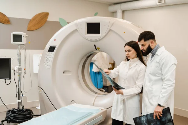 CT Computed tomography scan procedure to obtain detailed internal images of body and research on tumors in head, brain, and spine. Colleagues doctors discussing x-rays after CT scan of abdomen