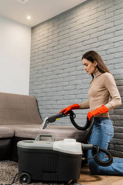 Dry cleaning extractor machine is spraying water and detergent close-up. Professional domestic cleaning service worker is removing dirt and dust from couch using dry cleaning machine