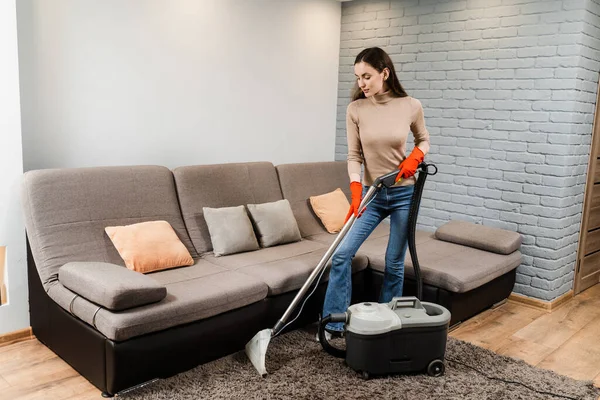 Dry cleaning extractor mop machine is spraying water and detergent on carpet. Professional domestic cleaning service worker is removing dirt and dust from carpet using dry cleaning machine mop