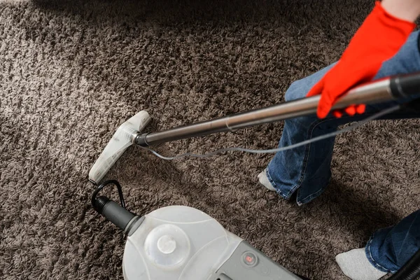 Housekeeper is extracting dirt from carpet using dry cleaning extractor mop machine. Cleaner girl is cleaning carpet with mop extraction machine for dry clean upholstered furniture
