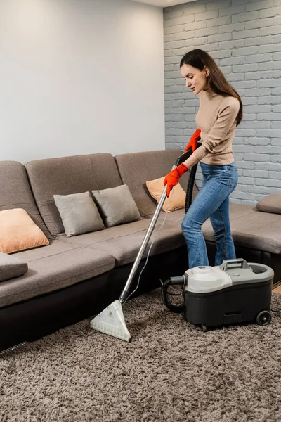 Professional domestic cleaning service worker is removing dirt and dust from carpet using dry cleaning machine mop. Dry cleaning extractor mop machine is spraying water and detergent on carpet