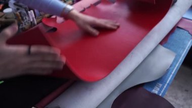 4k video leather craftsman is touching and checking quality of genuine leather roll in the workshop. Rolls of genuine leather of different colors in leather products workshop