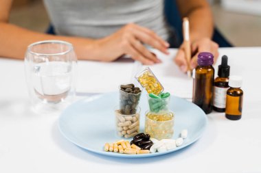 Nutritionist is writing prescription for biologically active supplements omega and zinc pills, antioxidants from aging, lecithin and adaptogen