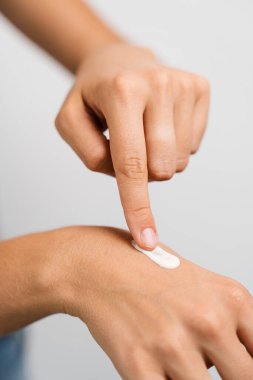 Girl applying hand moisturizer cream to protect skin from dryness in bedroom. Woman in bathrobe with hands moisturizing cream doing morning beauty routine