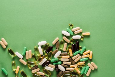 Many different pills for treatment and recovery health on green background. Set of omega and zinc pills, antioxidants from aging, lecithin and adaptogen