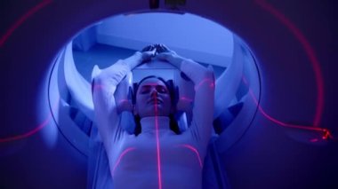 4k video CT x-ray examination of lung cancer with red lines and blue light in medical clinic top view. Patient girl lies on computed tomography bed and scanning lungs for diagnose lung cancer