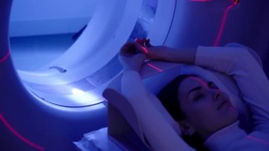 Tıbbi klinikteki kadının karın tomografisi 4K video görüntüsü. Kız hasta CT bilgisayarlı tomografi yapıyor. Göğüs röntgeni. Tomografi odasında karın taraması için..