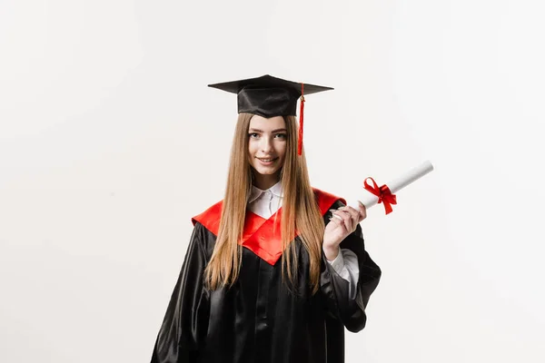 Graduate girl with master degree diploma in black graduation gown and cap on white background. Happy young woman successfully graduated from the university with honors