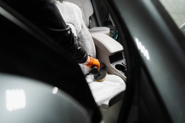 Smearing detergent on car textile seats using drill with brush for dry cleaning. Applying detergent on textile seat in car interior for dry cleaning