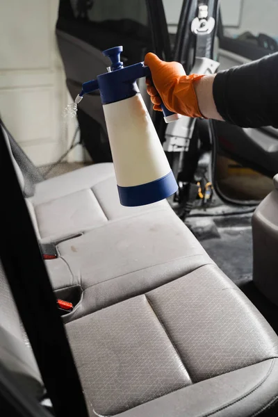 手袋の専門的なクリーナーは 汚れや汚れを除去するために車の座席に洗剤を注いでいます 車内のドライクリーニング繊維シート用スプレー洗剤 — ストック写真