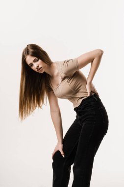 Tired girl holding on to her sore back. Scoleosis and osteochondrosis. Attractive girl feel spine pain because of spinal nerves compression