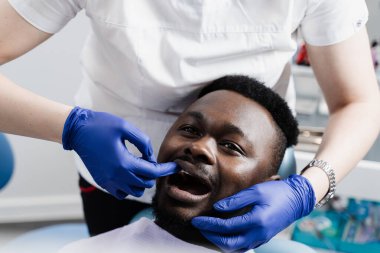 Stomatolojide diş hekiminde konsültasyon ve tedavi gören Afrikalı Amerikalı bir adam. Dişçi Afrikalı bir adamın dişlerini tedavi ediyor.