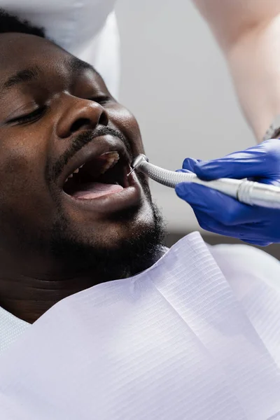 African man afraid of dentist. Dentist consults and drill teeth of frightened man in dentistry. Treatment of teeth and toothache in dentistry
