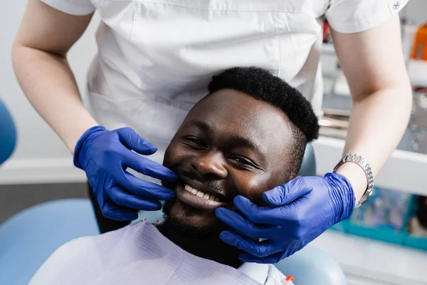 Dentist examines teeth of african man for treatment of toothache. Pain in teeth. Consultation with dentist in dentistry