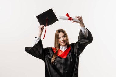 Graduate girl is graduating high school and celebrating academic achievement. Masters degree diploma in hands. Happy student in black graduation gown and cap is smiling on white background