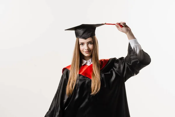 Graduate girl with master degree in black graduation gown and cap on white background. Happy young woman successfully graduated from the university with honors