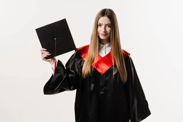 Graduate girl with master degree in black graduation gown and cap on white background. Happy young woman successfully graduated from the university with honors